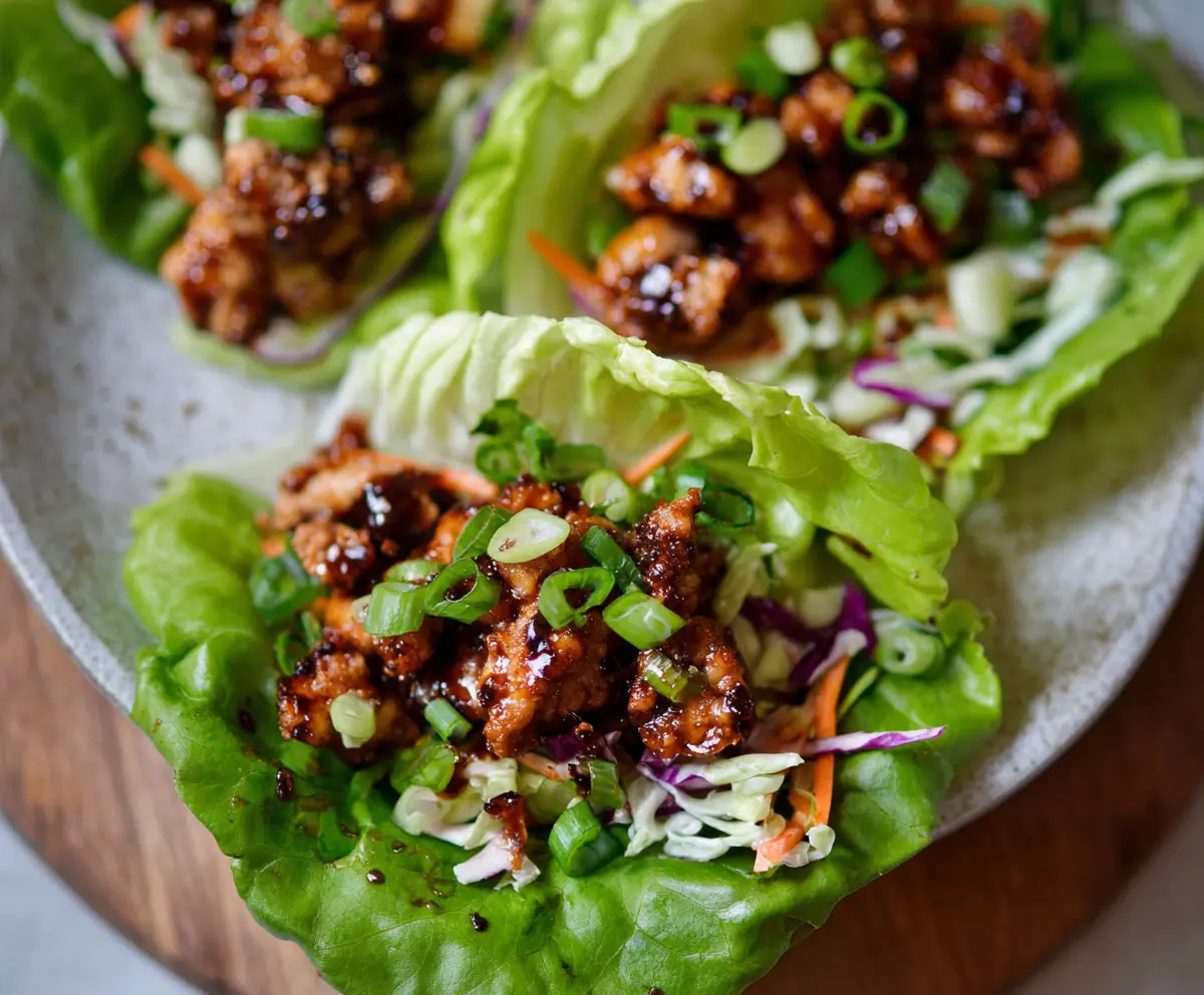 Delicious Hot Honey Chicken Lettuce Wraps served on a white plate with fresh greens.